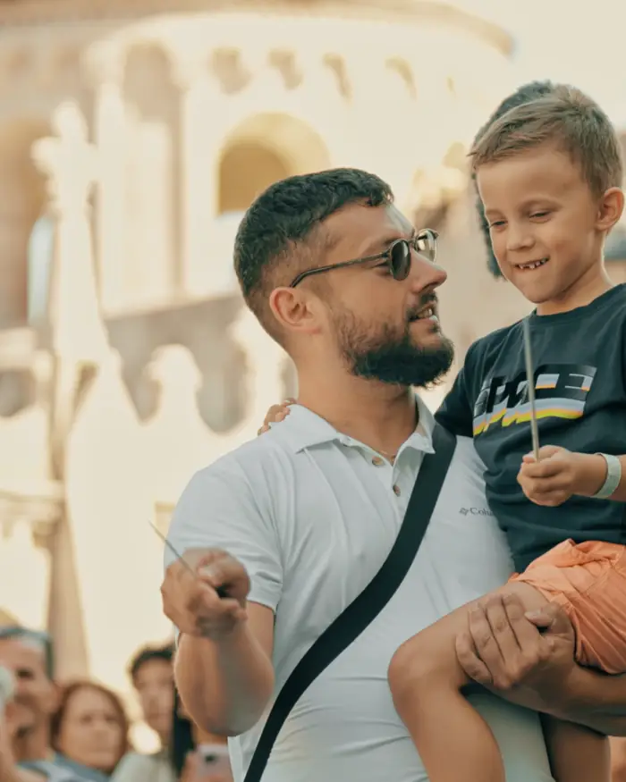 A father holds up his son, who is conducting